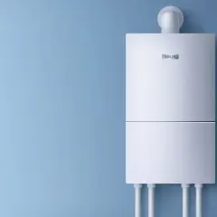 Biały bojler elektryczny zamontowany na niebieskiej ścianie.