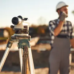 Precyzyjny niwelator na statywie czeka na geodetę. Ile geodeta bierze od punktu? To zależy od terenu i precyzji pomiaru.