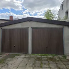 Dwa brązowe, segmentowe bramy garażowe w murowanym garażu. Zastanawiasz się, ile kosztuje wynajęcie garażu murowanego?