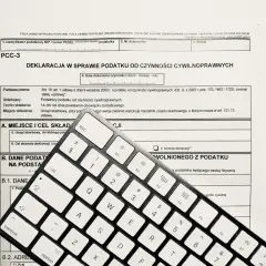 Formularz PCC-3 i klawiatura. Wpisz "podatek od nieruchomości" w tytule przelewu, aby poprawnie opłacić należność.