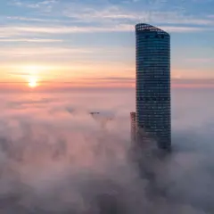 Wrocławski Sky Tower wyłaniający się z mgły o wschodzie słońca.