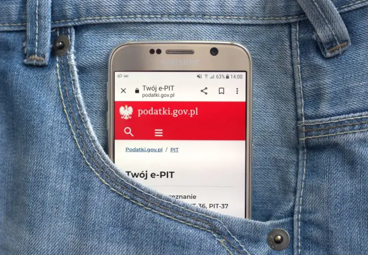 Telefon w kieszeni dżinsów wyświetla stronę podatki.gov.pl, gdzie można sprawdzić, jak zaokrąglić podatek od najmu.