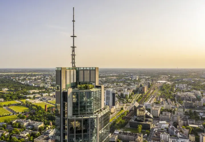 Widok z lotu ptaka na wieżowiec w Warszawie z anteną na szczycie. Zastanawiasz się, ile pięter ma Warsaw Tower? To imponująca budowla.