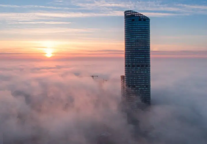 Wrocławski Sky Tower wyłaniający się z mgły o wschodzie słońca.