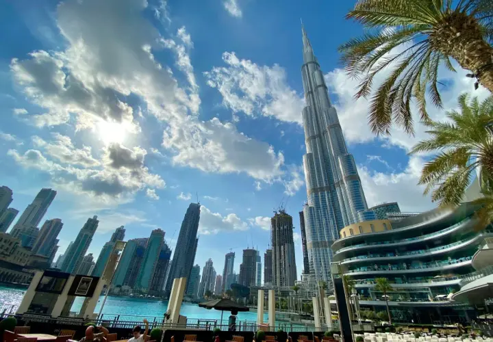 Widok na drapacze chmur w Dubaju, gdzie jest Burj Khalifa, z palmami i błękitnym niebem.