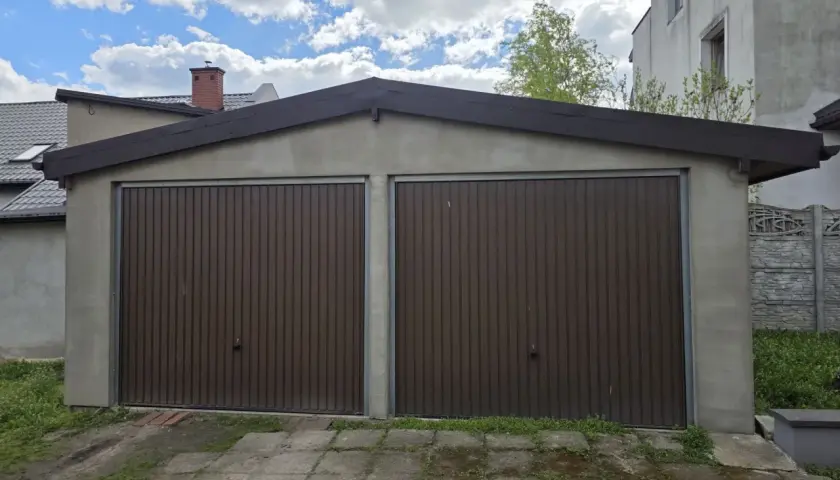 Dwa brązowe, segmentowe bramy garażowe w murowanym garażu. Zastanawiasz się, ile kosztuje wynajęcie garażu murowanego?