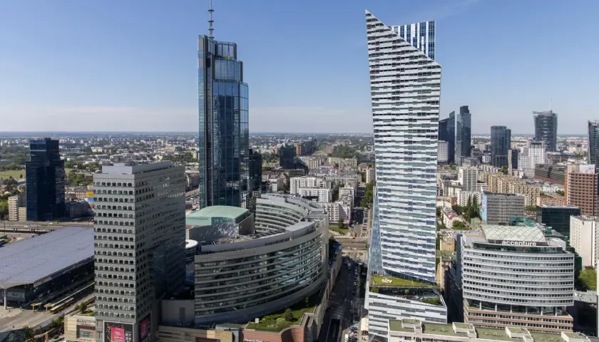 Warszawskie wieżowce, w tym najwyższy budynek w Warszawie, na tle błękitnego nieba.