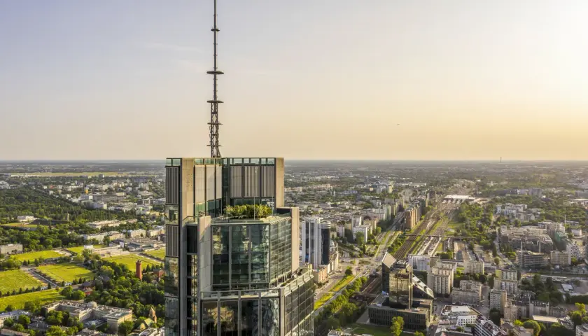 Widok z lotu ptaka na wieżowiec w Warszawie z anteną na szczycie. Zastanawiasz się, ile pięter ma Warsaw Tower? To imponująca budowla.