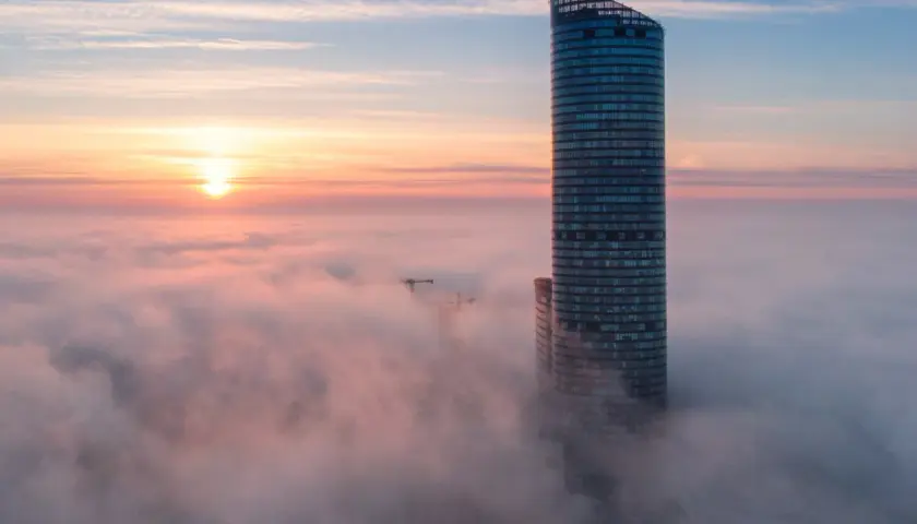 Wrocławski Sky Tower wyłaniający się z mgły o wschodzie słońca.