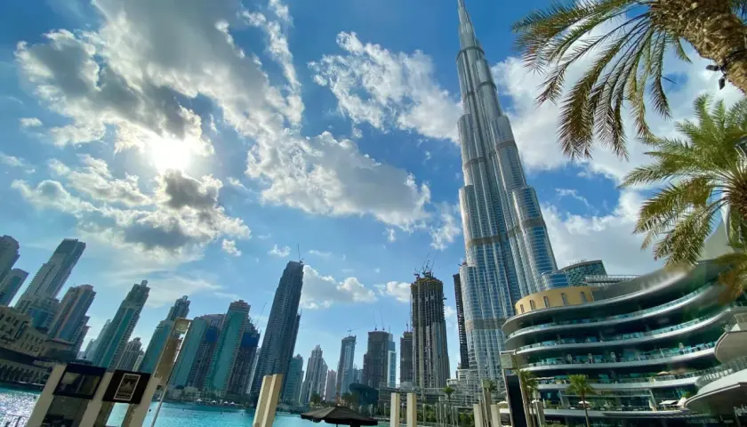 Widok na drapacze chmur w Dubaju, gdzie jest Burj Khalifa, z palmami i błękitnym niebem.