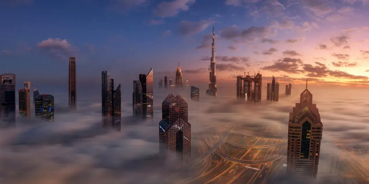 Wieżowce w chmurach, gdzie jest największy budynek na świecie. Wschód słońca nad Dubajem.