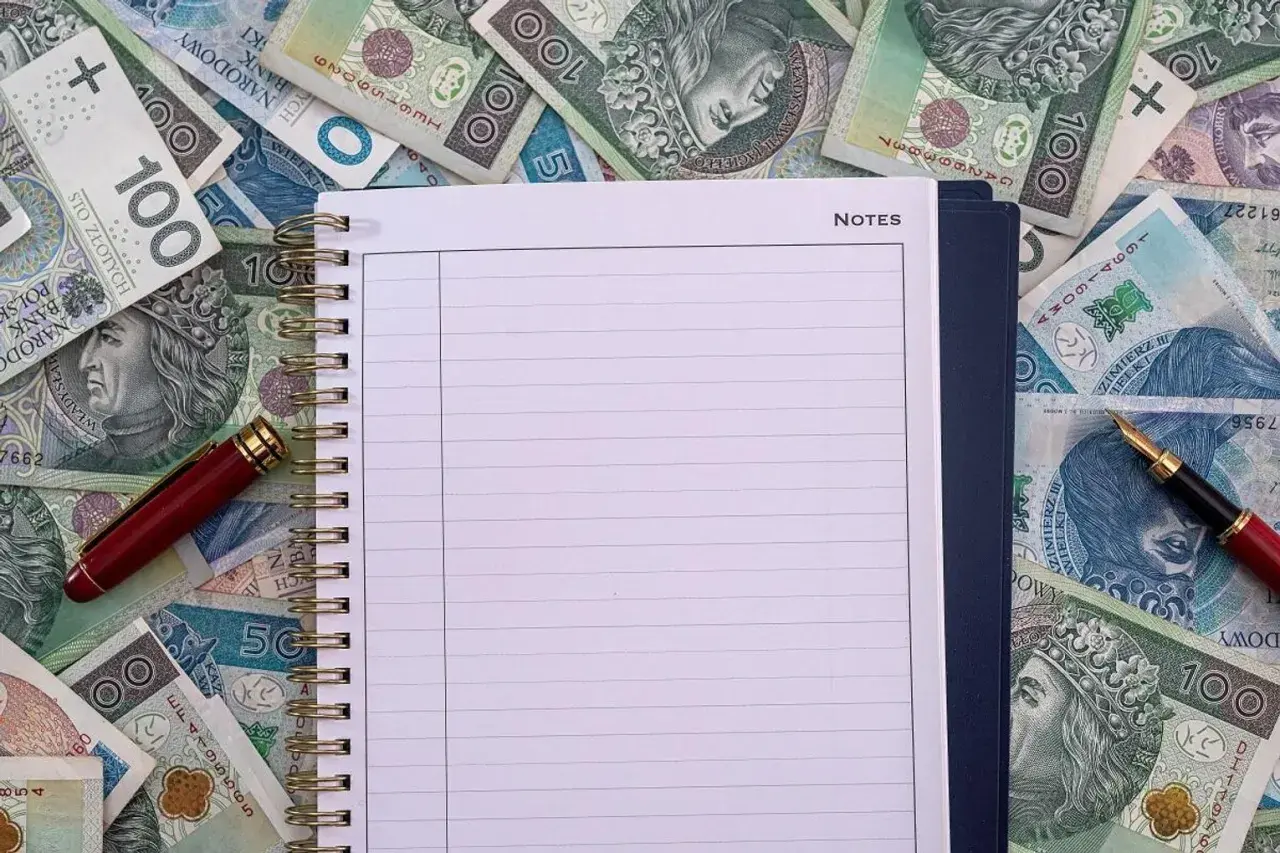 Notatnik i długopis na stosie polskich banknotów. Czy to miejsce na zapisanie, ile zarabia przewodniczący rady miasta?