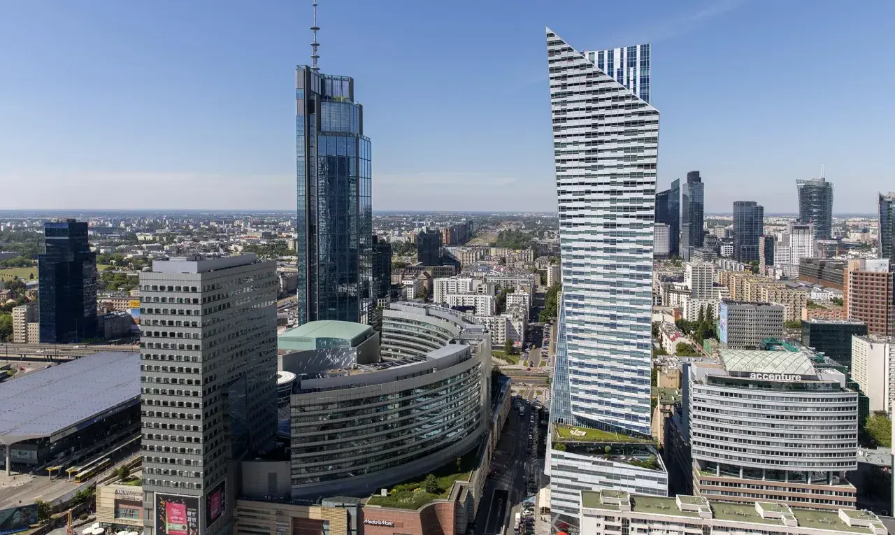 Warszawskie wieżowce, w tym najwyższy budynek w Warszawie, na tle błękitnego nieba.