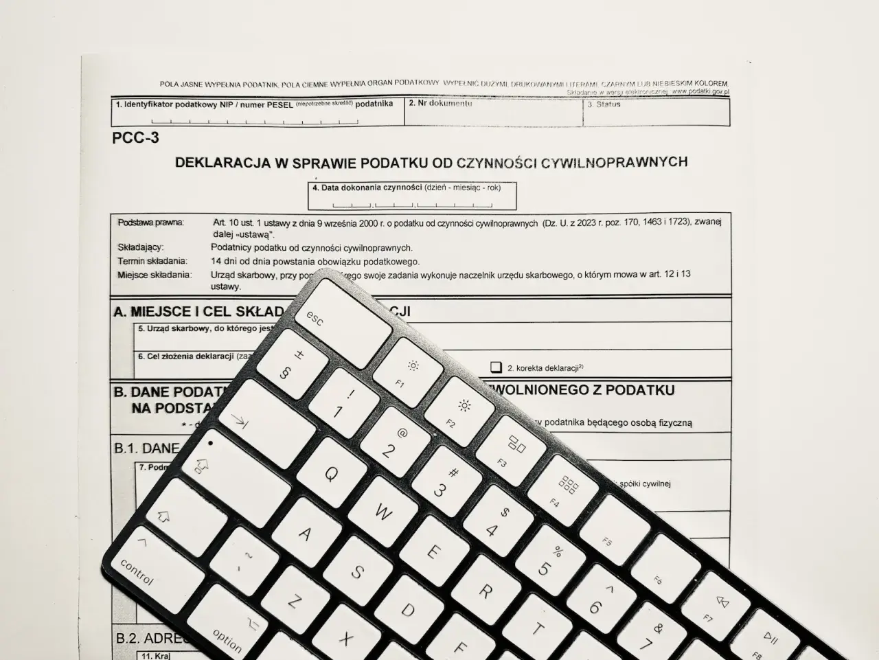 Formularz PCC-3 i klawiatura. Wpisz "podatek od nieruchomości" w tytule przelewu, aby poprawnie opłacić należność.