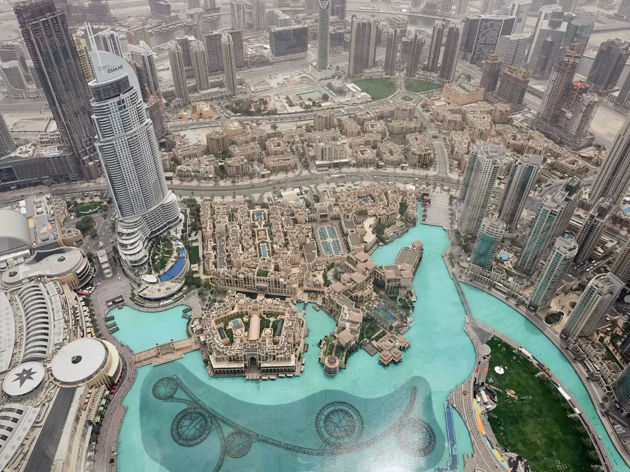 Widok z góry na Dubaj, z widoczną panoramą miasta, w tym budynkami i wodnymi atrakcjami. Zastanawiasz się, ile ma burdż chalifa?