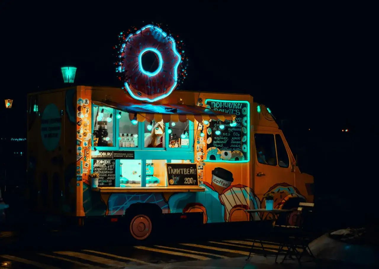 Kolorowy food truck z neonowym pączkiem i napisem 