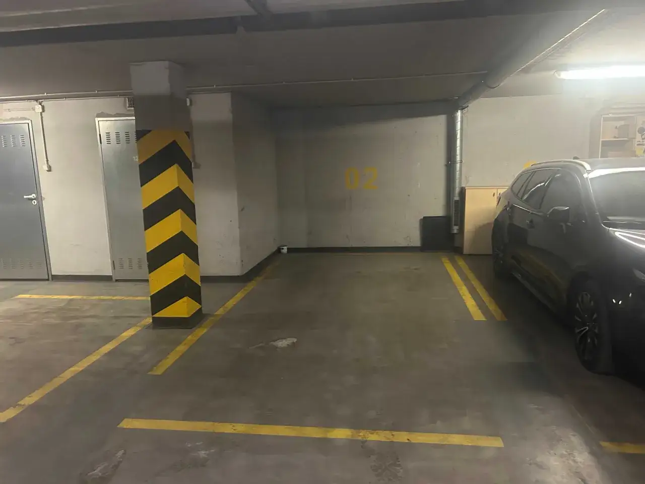 Miejsce parkingowe w garażu podziemnym w Warszawie, obok czarnego samochodu. Zastanawiasz się, ile kosztuje miejsce parkingowe w Warszawie?