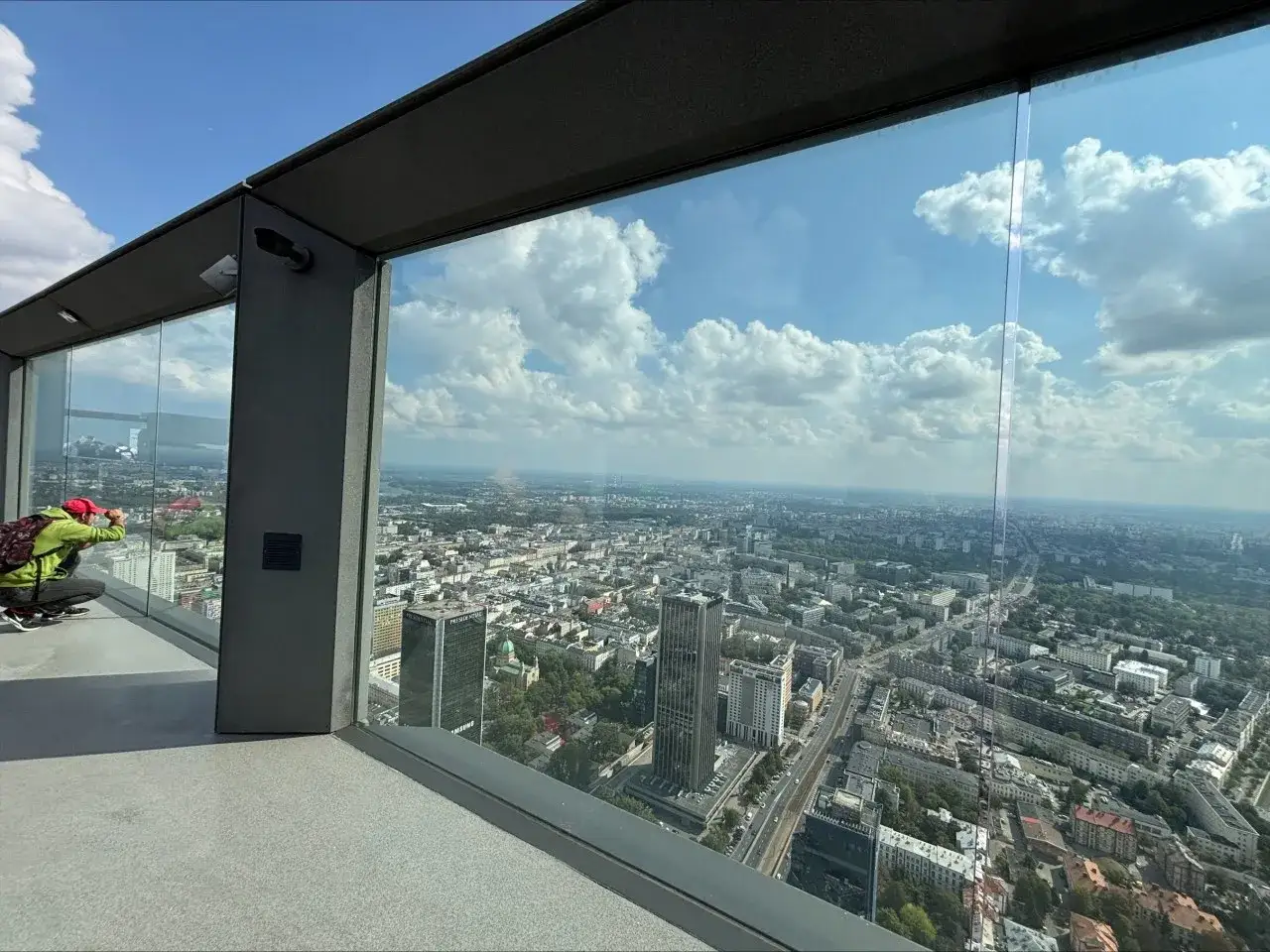 Widok z tarasu widokowego na miasto, gdzie jest najwyższy budynek w Polsce. Turysta robi zdjęcie panoramy.