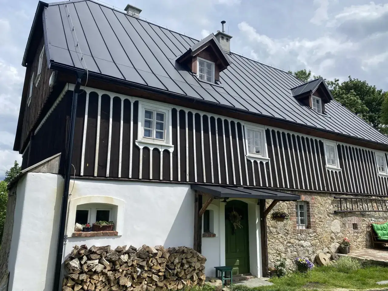 Stary dom z kamienia i drewna, z zielonymi drzwiami i stertą drewna. Ile lat musi mieć dom, żeby był zabytkiem?
