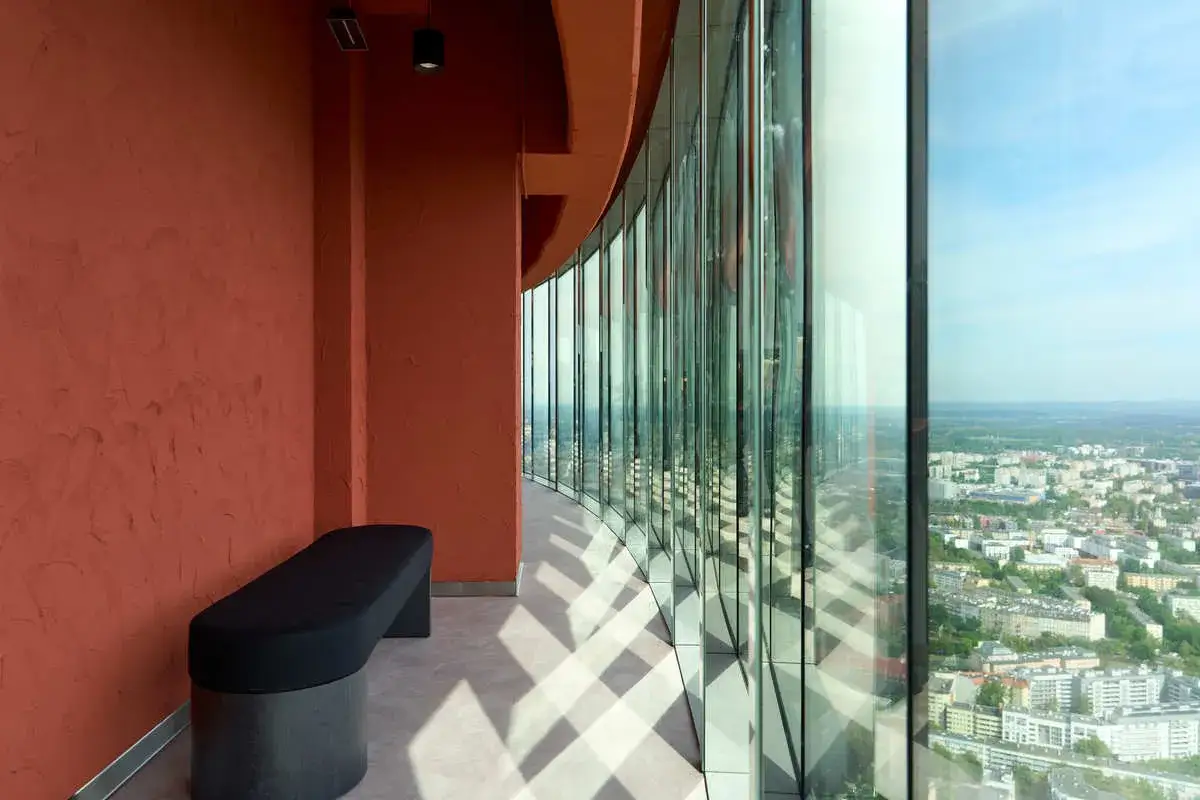 Wnętrze Sky Tower z ławką i widokiem na miasto. Trudno określić, ile pięter ma Sky Tower, ale z tej perspektywy widać wiele.