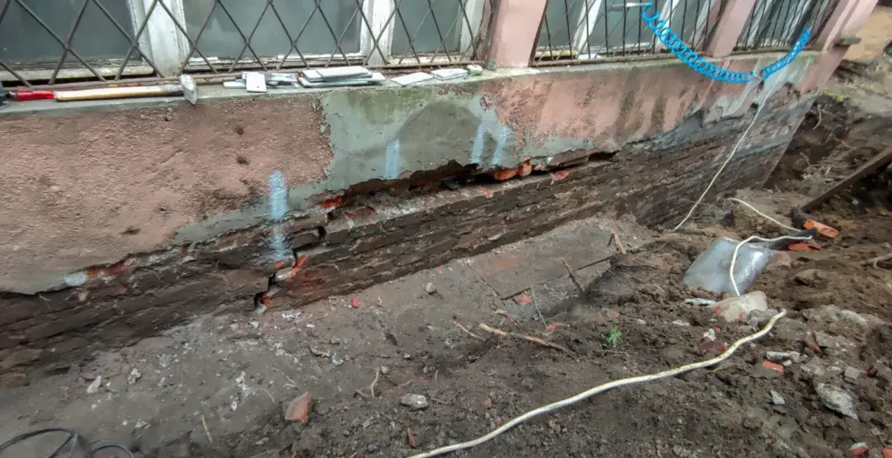 Uszkodzony fundament domu, widoczne pęknięcia cegieł. Trwają prace, które mogą wpłynąć na to, ile kosztuje ankrowanie domu.
