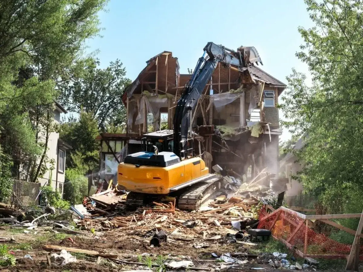 Koparka rozbiera dom. Zastanawiasz się, gdzie zgłosić rozbiórkę budynku? Sprawdź lokalne przepisy.