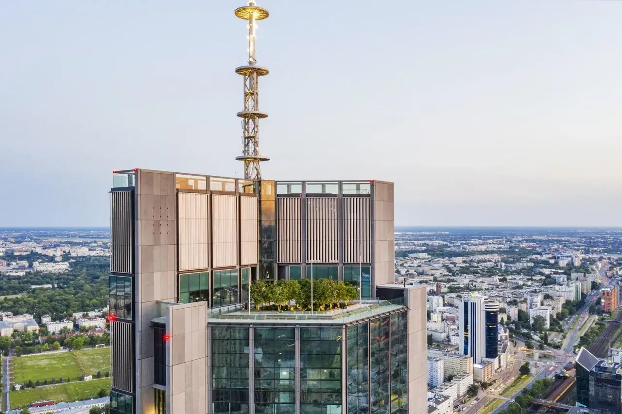 Warsaw Tower z tarasem zieleni i anteną. Trudno ocenić, ile pięter ma warsaw tower, ale jest bardzo wysoka.