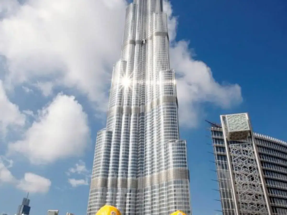 Burj Khalifa, zaprojektowany przez firmę Skidmore, Owings & Merrill, lśni w słońcu na tle błękitnego nieba z chmurami.
