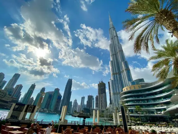 Widok na drapacze chmur w Dubaju, gdzie jest Burj Khalifa, z palmami i błękitnym niebem.